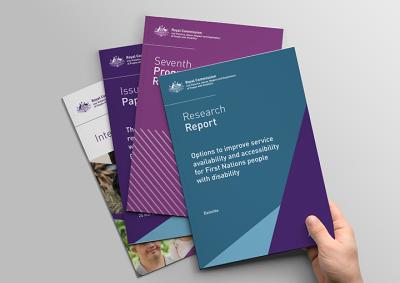 Four Royal Commission publications fanned out with a hand picking up the top Research Report